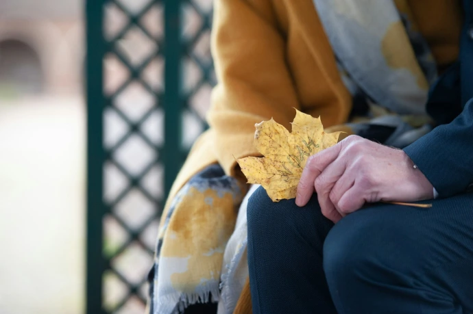 una persona sentada en un banco sosteniendo una hoja